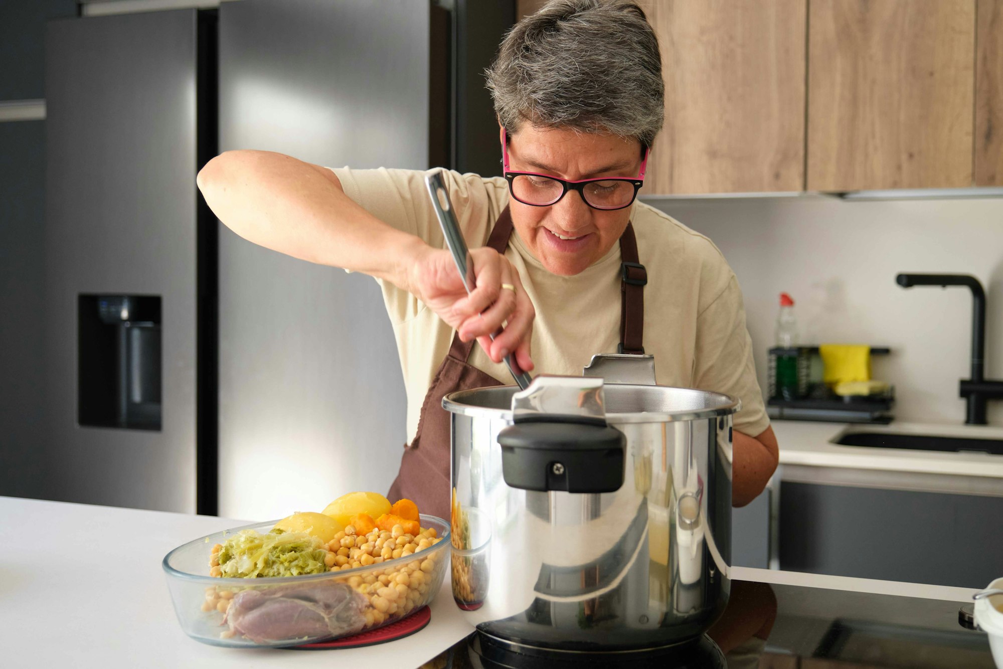 Mature Spanish woman cooking cocido, typical Spanish dish.